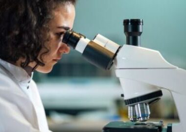 Female scientist viewing a sample through a microscope.