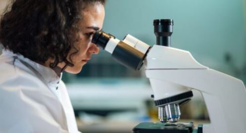 Female scientist viewing a sample through a microscope.