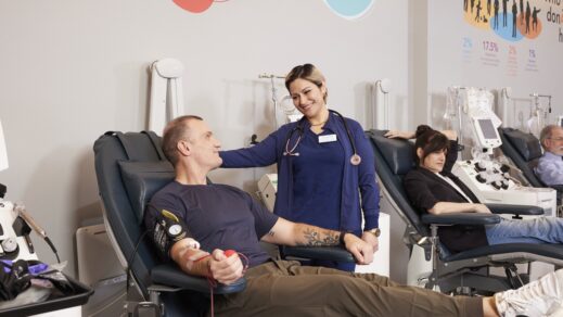 Blood donor in donation chair while being attended to by MBC phlebotomist.