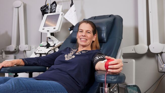 Blood donor squeezing foam heart in her hand as she donates blood.